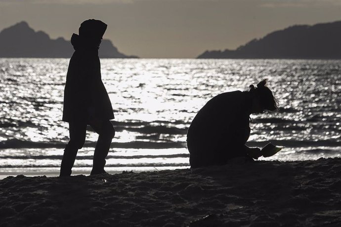 Archivo - Dos personas durante la limpieza de pellets organizada por la Asociación para la Defensa Ecológica de Galicia (ADEGA) en las playas de Cangas de Morrazo, a 20 de enero de 2024.