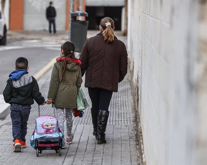 Archivo - Imagen de archivo de un niño y una niña, acompañados de una mujer, caminando hacia un colegio público.