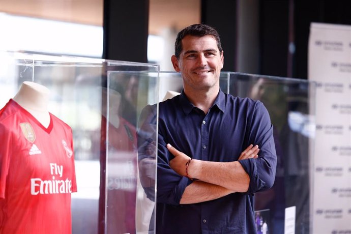 Iker Casillas posa al lado de una de las camisetas de la exposición 'Pegada al Corazón'