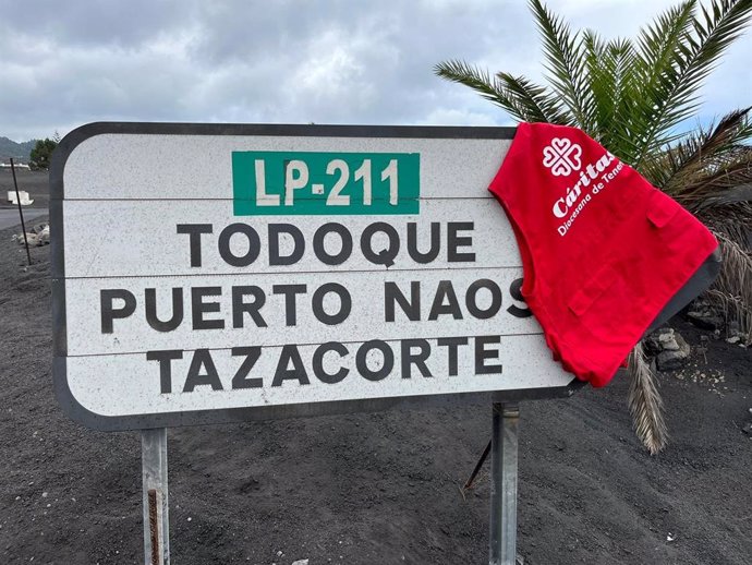 Un chaleco de Cáritas Diocesana de Tenerife cuelga de un cartel en el que figuran tres de los puntos afectados por el volcán Tajogaite