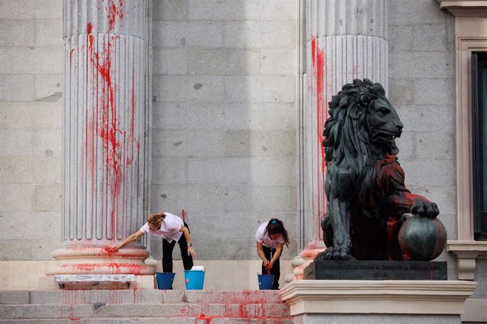 Archivo - Dos operarias limpian el león del Congreso tras ser pintado por una protesta por la creciente criminalización de la ciencia y el movimiento climático, frente al Congreso de los Diputados, a 30 de marzo de 2023, en Madrid (España)