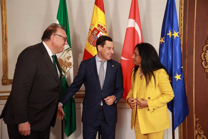 El presidente de la Junta de Andalucía, Juanma Moreno (c), saluda a la embajadora de Turquía en España, Nüket Küçükel (d), en prese4ncia del consejero de Turismo y Andalucía Exterior, Arturo Bernal (i).