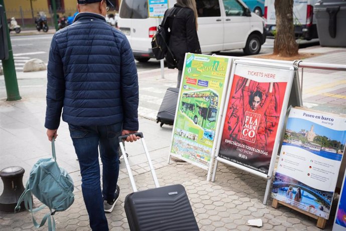 Archivo - Un turistas pasa junto a unos carteles con ofertas de ocio turísticas.