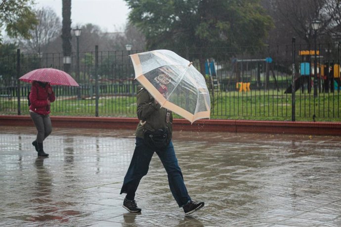 Archivo - Dos personas se protegen de la lluvia bajo su paraguas. A 9 de febrero de 2024, en Sevilla (Andalucía, España). La borrasca 'Karlotta' activa avisos por lluvia, viento y oleaje en todas las provincias andaluzas.