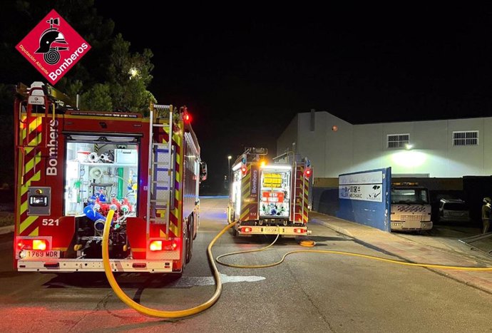 Bombers treballen en l'extinció d'un incendi en un taller de cotxes