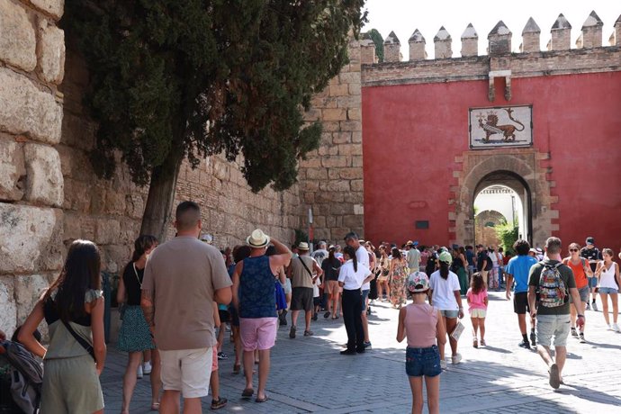 Archivo - Turistas en la Plaza del Triunfo guardan cola y se disponen a entrar en el Real Alcázar de Sevilla, en foto de archivo.