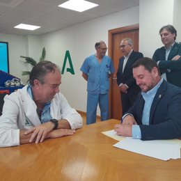 El director gerente del HUVM, Miguel A. Colmenero, firmando colaboración, con representante de la Casa de Ronald McDonald.