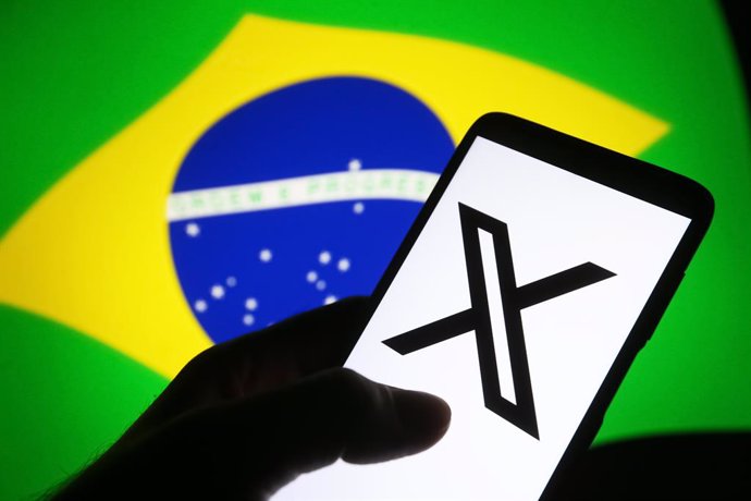 September 8, 2024, Ukraine: In this photo illustration, a social media platform X (former Twitter) logo is seen on a smartphone and flag of Brazil on a pc screen. Supreme Court of Brazil orders blocked Ilon Musk's X platform, reportedly by media.