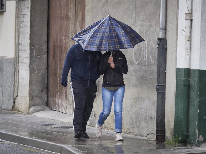 Archivo - Dos personas se protegen de la lluvia con un paraguas.