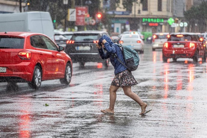 Archivo - Una mujer anda por la calle bajo la lluvia, a 3 de julio de 2023, en València