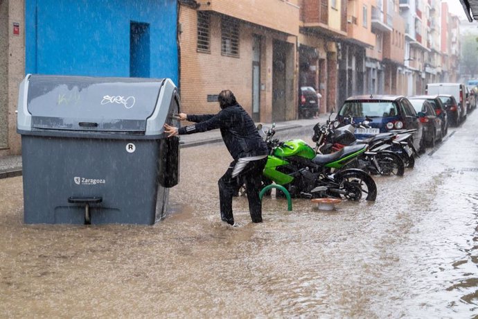 Un hombre sujeta un contenedor en medio de una balsa de agua en Zaragoza