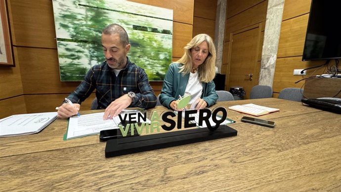 El alcalde de Siero, Ángel García, firma el acuerdo presupuestario con la concejala de la Plataforma Vecinal de La Fresneda, Alejandra Cuadriello.