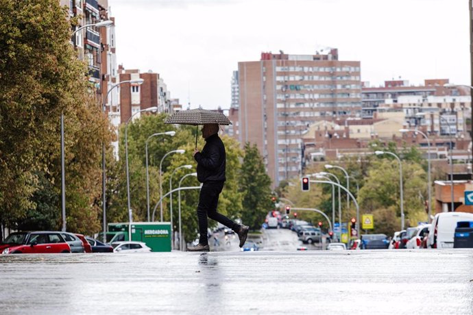 Archivo - Un hombre se protege de la lluvia con un paraguas, en Madrid.