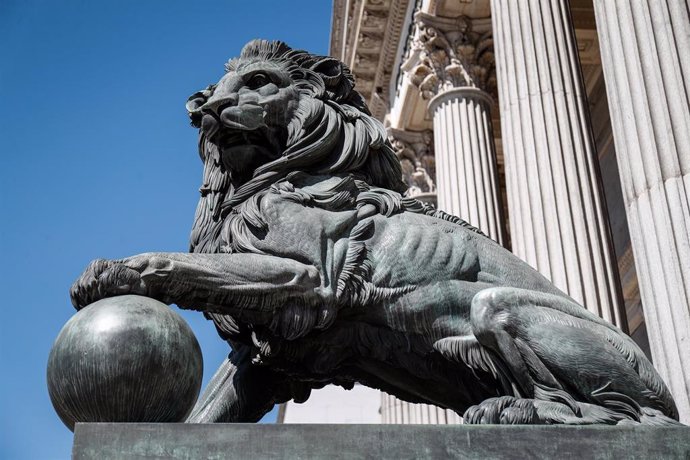 Archivo - Uno de los emblemáticos leones que se encuentran delante de la fachada del Congreso de los Diputados en la Plaza de las Cortes de Madrid.