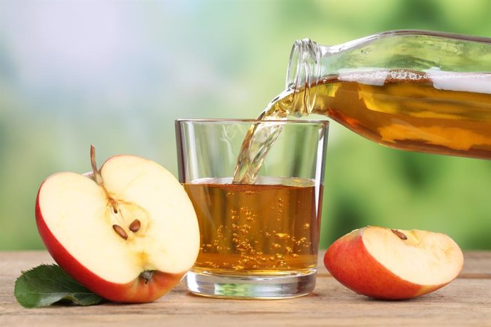 Archivo - Apple juice pouring from red apples fruits in summer into a glass