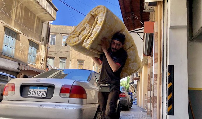 Un hombre traslada una manta para los desplazados en la capital de Líbano, Beirut, tras la oleada de bombardeos de Israel contra territorio libanés (archivo)