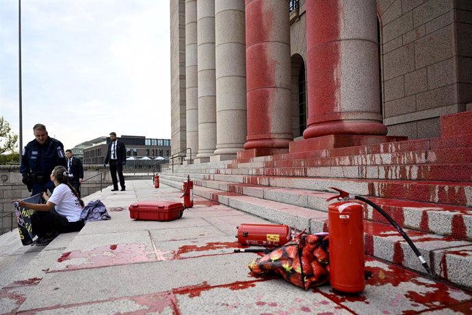 25 September 2024, Finland, Helsinki: A police officer talks to a protester outside the House of Representatives after protesters painted its pillars in red. Photo: Emmi Korhonen/Lehtikuva/dpa