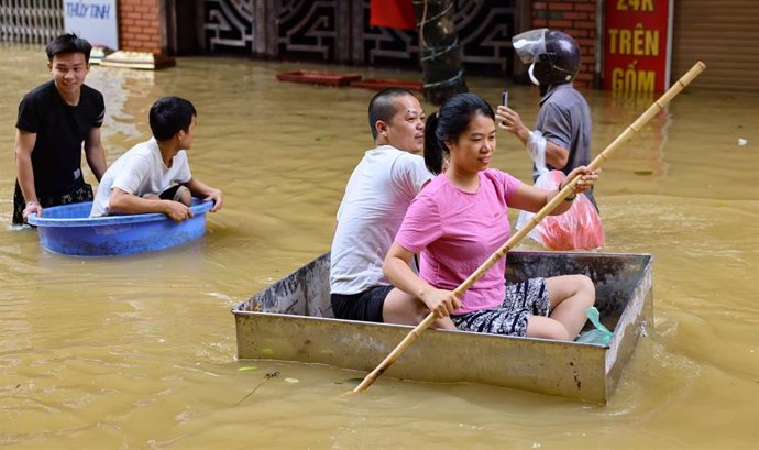 Varias personas en una calle anegada de Hanoi tras el paso del tifón 'Yagi'