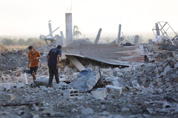 Palestinos inspeccionan los restos de un edificio destruido tras ataques de Israel