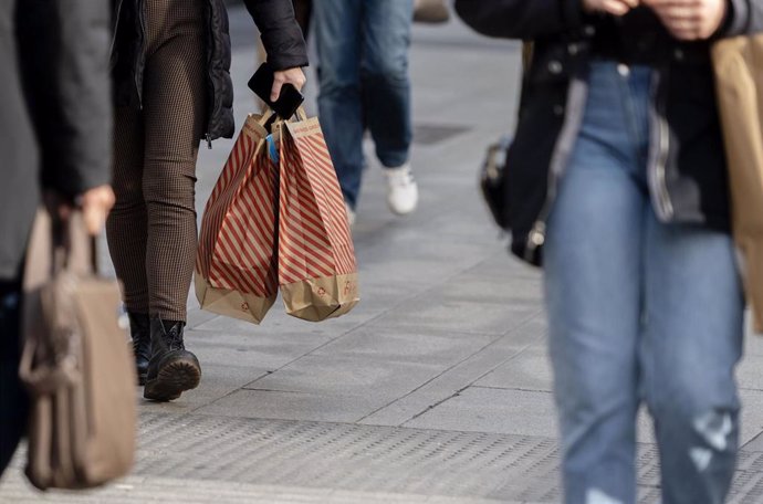 Archivo - Una mujer camina con bolsas con compras