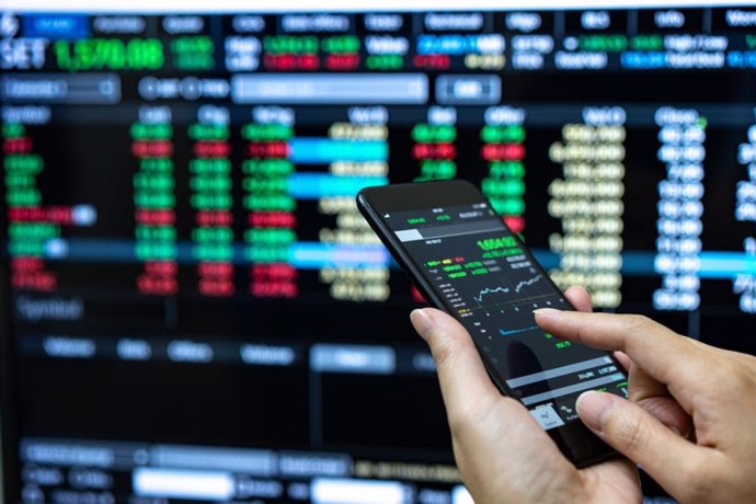 Archivo - Businessman checking stock market data. He using a mobile phone.