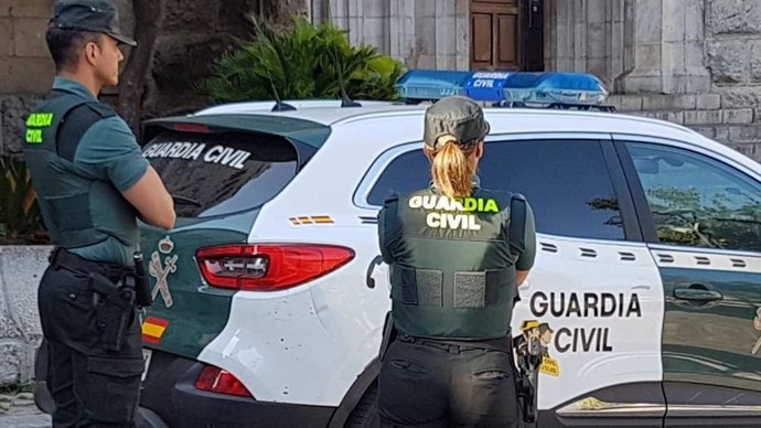 Archivo - Una agente y un coche de la Guardia Civil.