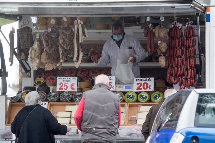 Archivo - Un hombre y una mujer compran en un mercadillo de Castro Riberas de Lea, Galicia (España) a 27 de enero de 2021. A las 00,00 de este miércoles han entrado en vigor las nuevas restricciones implantadas por la Xunta para luchar contra la pandemia 