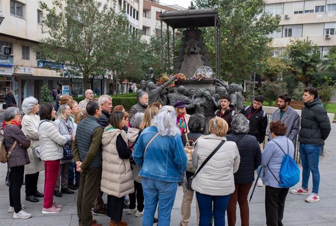 Turistas en una parada frente al monumento a la Virgen del Rocío en la capital en su visita guiada por Huelva.