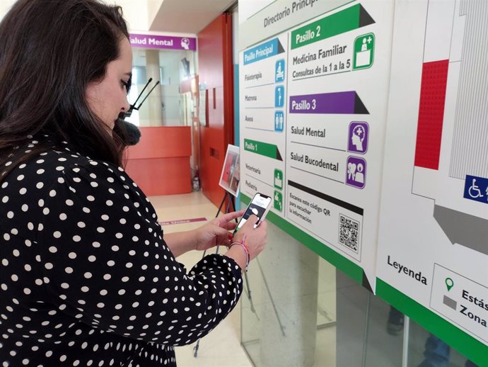 Una mujer accede con su smartphone a la información del cófigo QR de la nueva cartelería cognitiva instalada en el centro de salud Mérida Norte.