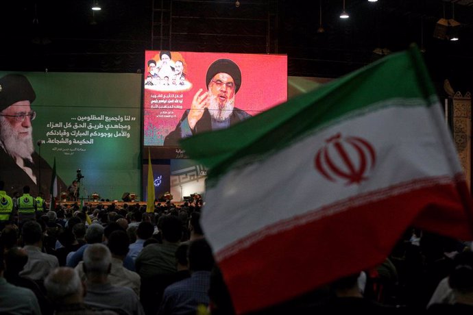 Archivo - May 24, 2024, Beirut, Beirut, Lebanon: A pro-Iranian Hezbollah supporters wave the Iranian flag as the party Secretary General Hassan Nasrallah addresses the audience through a giant screen during a mass rally in Beirut southern suburb to mark t