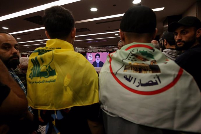 Archivo - Dos jóvenes llevan la bandera de Hezbolá (izq) y la bandera del partido hutí yemení Ansar Alá (dcha)