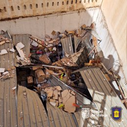 Los escombros de la pared de la vivienda que cayó debido al incendio provocarón daños en el techo de un almacén contiguo en el centro de Málaga.