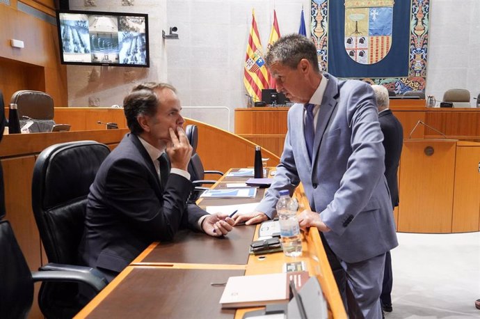 El consejero del departamento de Hacienda, Interior y Administración Pública del Gobierno de Aragón,  Roberto Bermúdez de Castro, a la izquierda, conversa con el diputado popular Antonio Romero en el Pleno de las Cortes de esta semana.