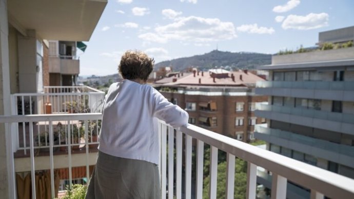 Una señora mayor mira desde un balcón de Barcelona (Catalunya)