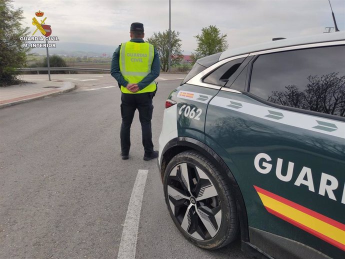 Agente de la Guardia Civil junto a su coche patrulla