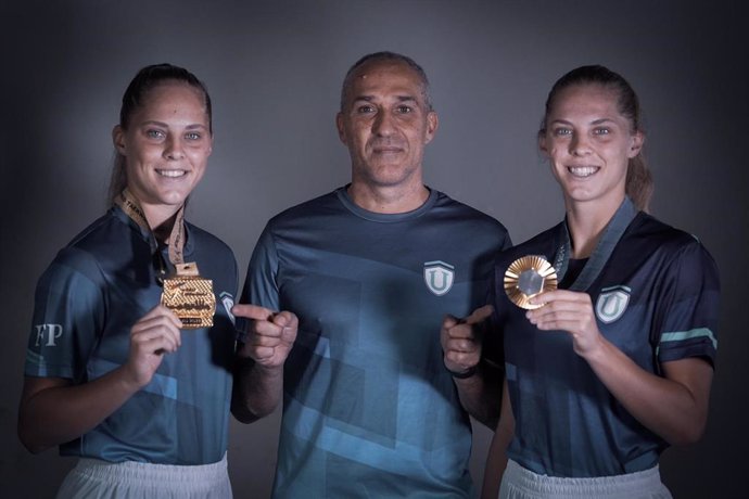 Luana Marton y Viviana Marton posan con su medalla de oro en el Mundial 2023, y los Juegos Olímpicos de 2024, respectivamente, junto con su entrenador Jesús Ramal