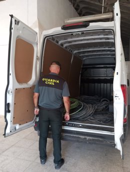 Un agente de la Guardia Civil con la furgoneta y el cableado recuperado.