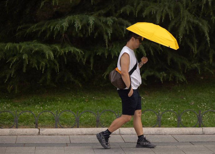 Archivo - Un hombre se resguarda del sol bajo un paraguas, a 18 de julio de 2024, en Madrid (España). La primera ola de calor del verano pone hoy en aviso amarillo o naranja a casi toda España, con temperaturas que superarán los 40 grados en algunos punto