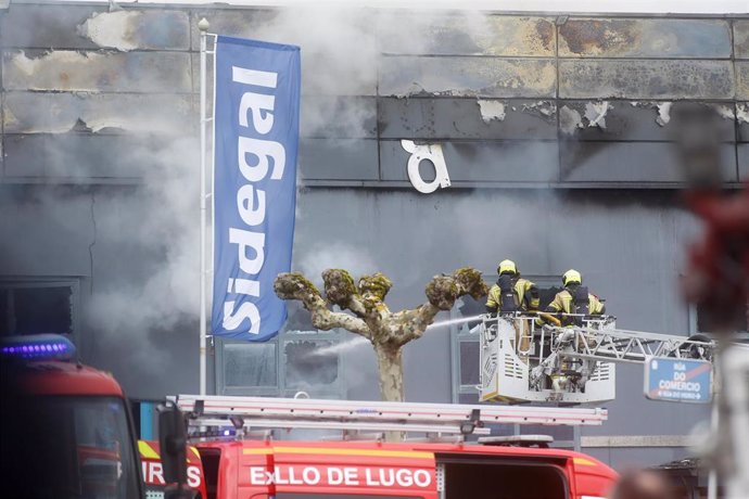 Archivo - Bomberos apagan con un agua el fuego de una nave de desguace en el polígono de O Ceao, a 26 de marzo de 2024, en O Ceao, Lugo, Galicia (España). Los servicios de emergencia tratan de sofocar un incendio en la nave de la empresa Desguaces Sidegal