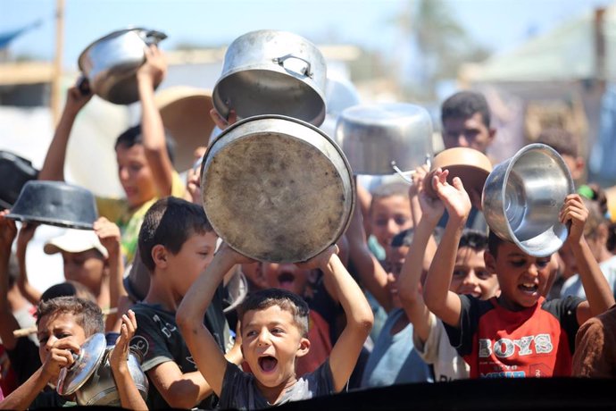 Archivo - Un grupo de niños palestinos guarda su turno para recibir comida en un campo de desplazados de la Franja de Gaza.