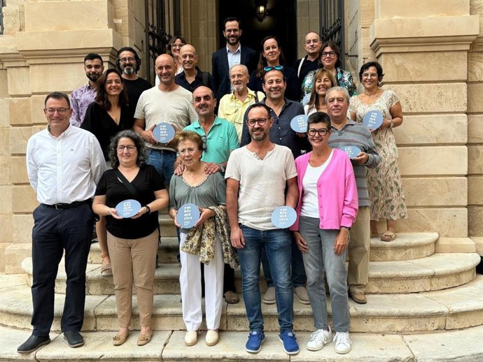 Representantes de los comercios emblemáticos de Maó reciben su placa distintiva.