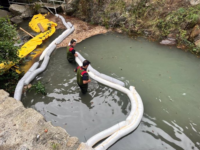 Los bomberos instalando barreras para frenar el vertido de gasóleo