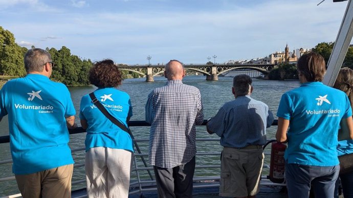 Voluntarios de CaixaBank acompañan a personas mayores en un paseo en barco por el Guadalquivir.