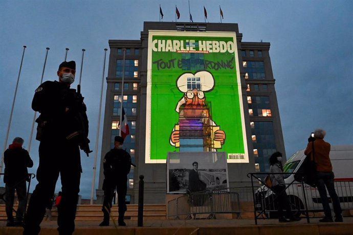 Archivo - Agentes de policía hacen guardia mientras se proyectan caricaturas del periódico satírico francés Charlie Hebdo en la fachada de un hotel.