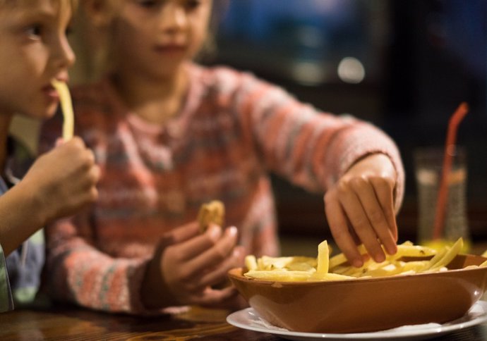 Archivo - Niños comiendo patatas