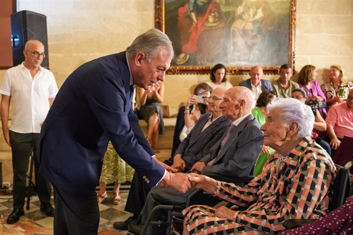 Sanz saluda en la Sala Capitular del Ayuntamiento a uno de los sevillanos centenarios homenajeados.