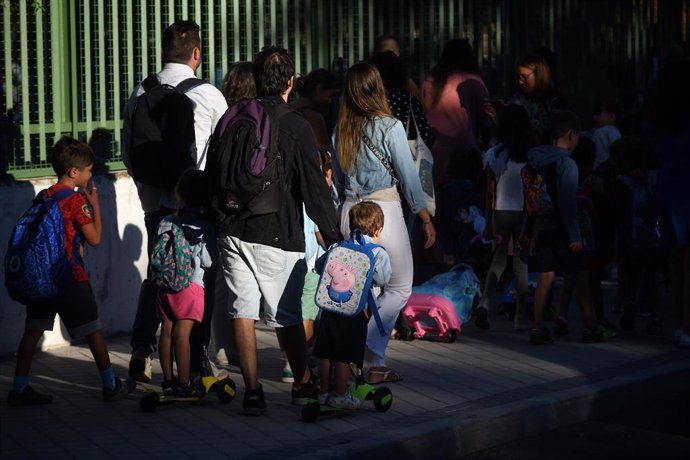 Archivo - Niños y padres hacen cola para entrar al colegio