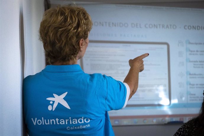 Archivo - Una voluntaria de CaixaBank imparte una sesión de educación financiera