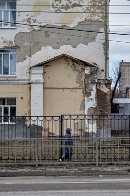 Archivo - March 10, 2023, Voronezh, Russia: Woman in front of the facade of the old school building on the street of Voronezh in early spring. With the beginning of spring, warming came to Voronezh.