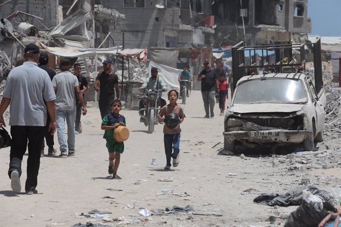 Archivo - Imagen de archivo de niños en la ciudad de Jan Yunis, en la Franja de Gaza, acuden con ollas a un punto de reparto de alimentos